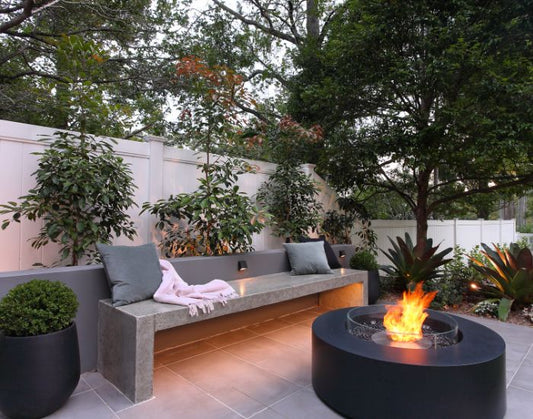 View of the EcoSmart Fire Ark 40 Bioethanol Fire Pit Table in the colour graphite, with a fire screen next to a bench